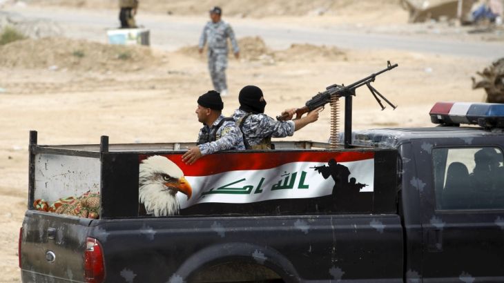 Iraqi security forces ride on a military vehicle with their weapons in Tikrit
