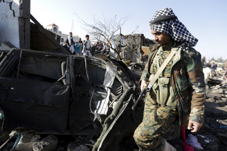 A Houthi fighter walks at the site of an air strike at a residential area near Sanaa Airport [REUTERS]