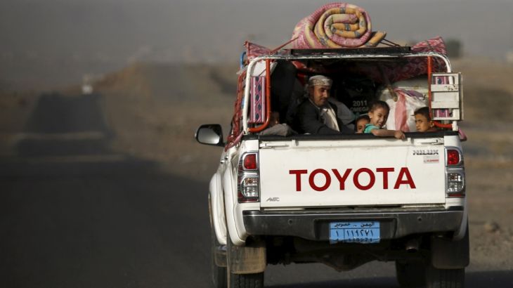 Man and his children ride on the back of a pick-up truck with their luggage as they flee Saudi-led air strikes in Sanaa