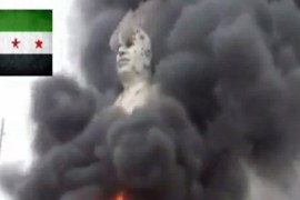 An image grab taken from a video uploaded on YouTube shows flames rising from a statue of late Syrian president Hafez al-Assad in al-Raqqa [AFP]