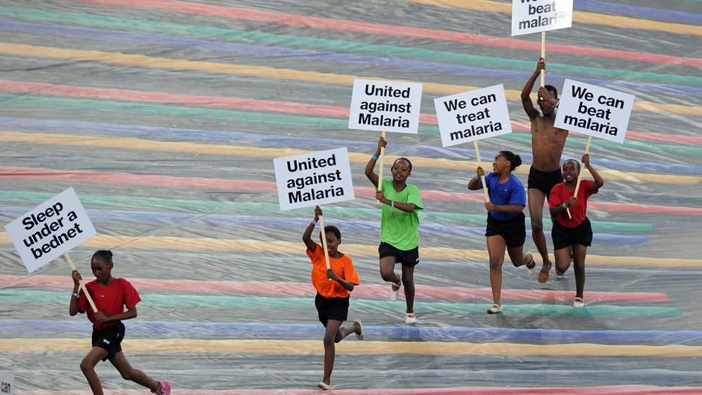 Children run with advertising banners highlighting the fight against malaria [Getty Images]