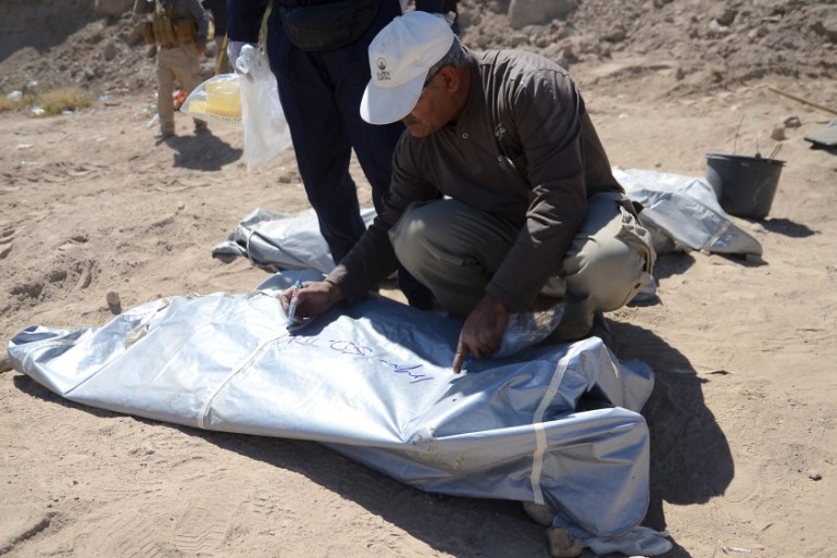 A member from the Iraqi forensic team writes on the body bag of remains belonging to Shi''ite soldiers from Camp Speicher who have been killed by Islamic State militants at a mass grave in Tikrit