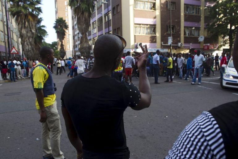 South African man gestures towards a group of foreign nationals during anti-foreigner violence in Durban