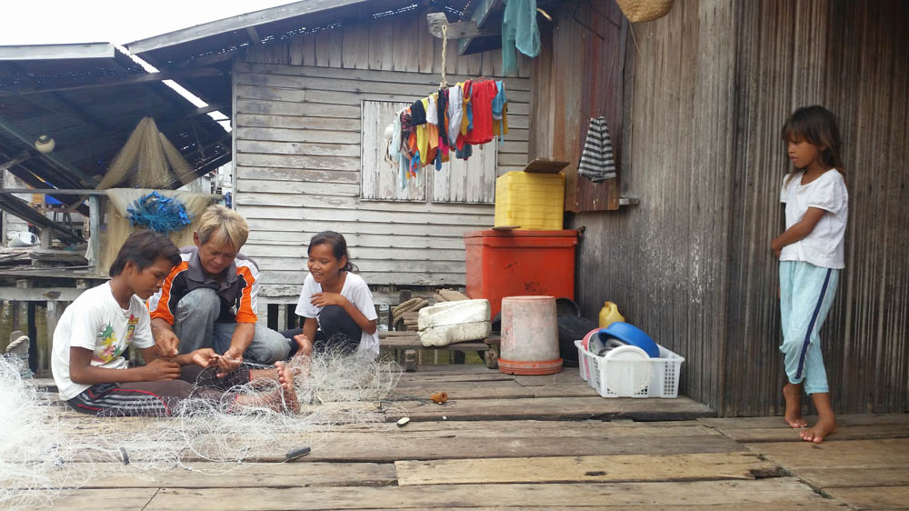 A Bajau Laut father teaches his children how to mend a net [Chan Tau Chou/Al Jazeera] 
