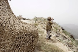 A Saudi soldier looks through binoculars at Saudi Arabia''s border with Yemen