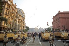 Egyptian military helicopters fly overhead as army soldiers stand guard at an entrance to Tahrir Square, in Cairo, Egypt [AP]