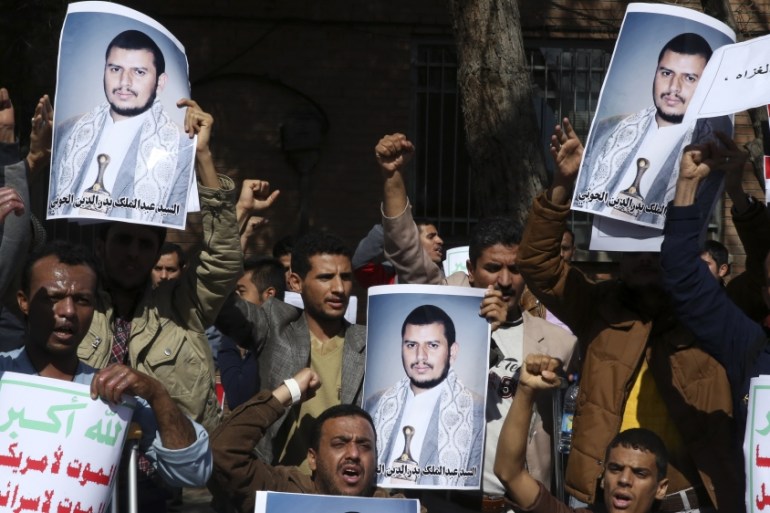 Yemeni men chant slogans while holding posters of Houthi rebel leader [AP]