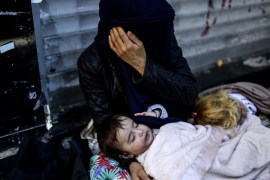 A Syrian refugee woman covers her face as she begs with her children on the street in the Beyoglu district of Istanbul [AFP]