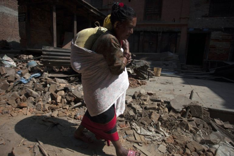 A Nepalese earthquake survivor carries her belongings a day after a major earthquake [EPA]