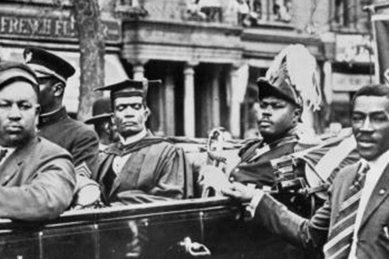 Marcus Garvey sits in the back of a car in a parade through Harlem circa 1920 in New York City [Getty]