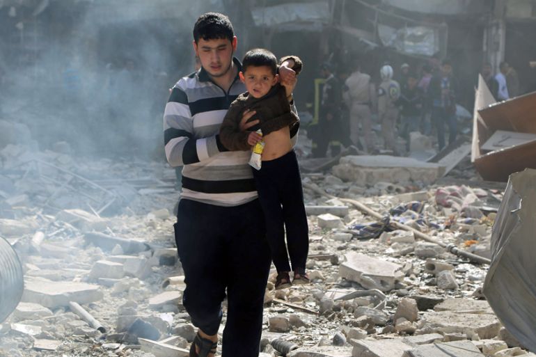 A man carries a boy over debris at a site damaged by what activists said was a barrel bomb dropped by forces loyal to Syria''s president Bashar Al-Assad in Aleppo''s al-Saliheen district