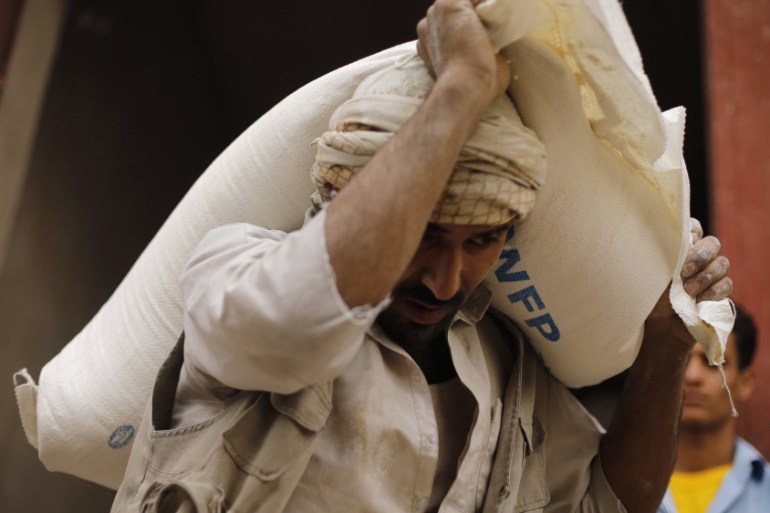 A worker carries a wheat flour bag at a WFP distribution center in Sanaa
