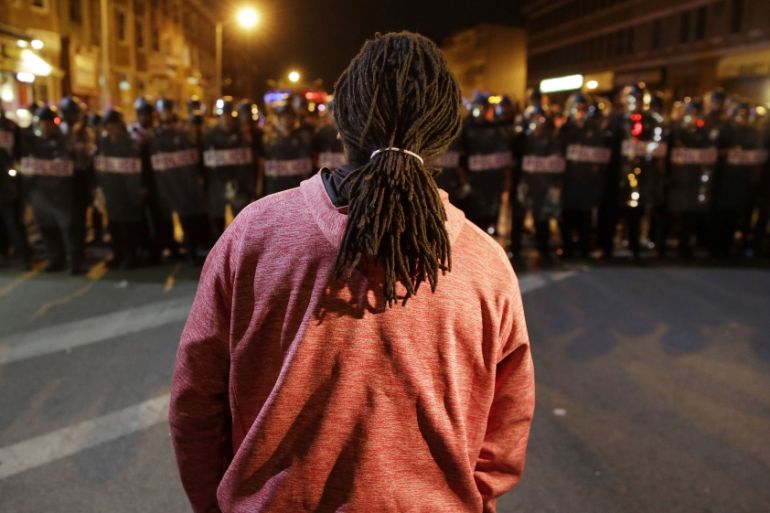 A protester watches as police enforce curfew in Baltimore [AP]