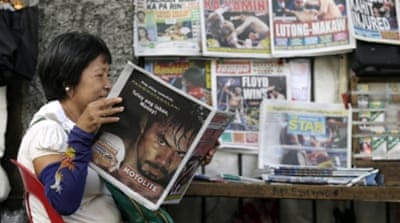 A Filipino reads a newspaper reporting on the boxing match in Manila [EPA]