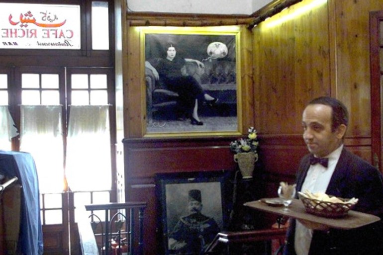 An Egyptian waiter walks in front of a picture of Egyptian Diva Umm Kulthum at the historical Cafe Riche [AFP]