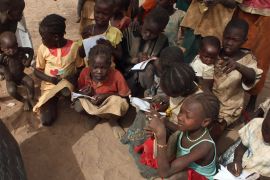 Refugee children copy notes from a chalkboard during an open-air English lesson under a tree at the Yida camp in South Sudan''s Unity State