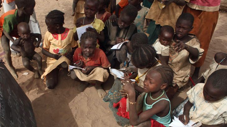 Refugee children copy notes from a chalkboard during an open-air English lesson under a tree at the Yida camp in South Sudan''s Unity State