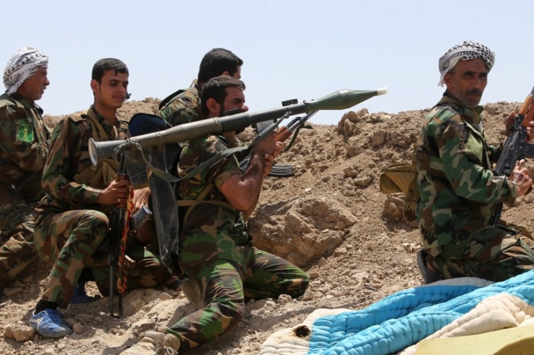 Shia fighters from the popular committees fire towards ISIL positions in Anbar province [AFP]