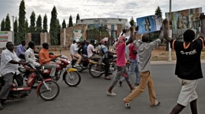 Protesters walk past the headquarters of the ruling party in Burundi [AFP]