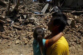 A man carrying a girl walks along the street near collapsed houses after last week''s earthquake in Bhaktapur