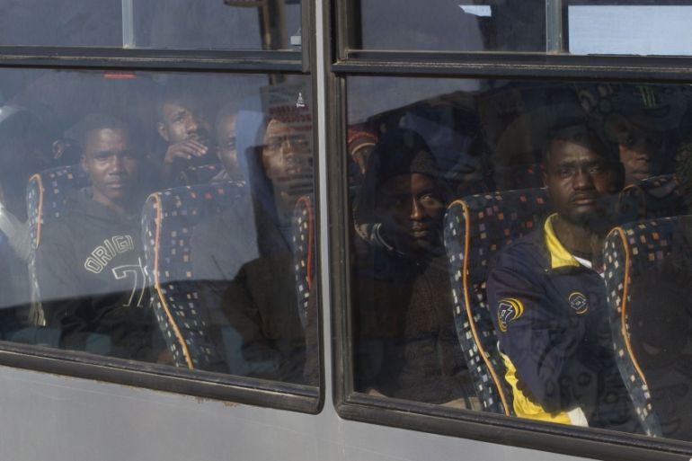 Rescued migrants sit on a bus after disembarking from an Italian Coast Guard ship