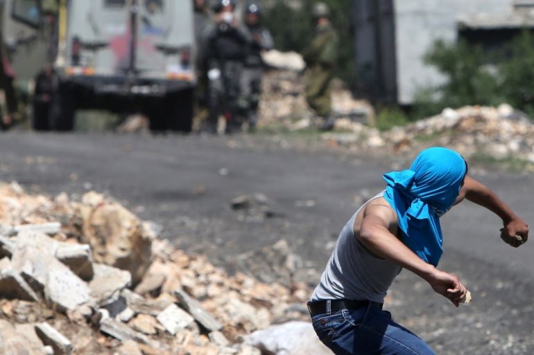 A Palestinian protestor throws stones towards Israeli security forces during clashes in the occupied West Bank [AFP]