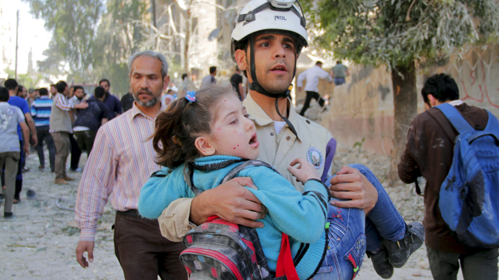 A civil defence member holds a rescued schoolgirl after what activists said was a barrel bomb dropped by forces loyal to Syria''s President Bashar al-Assad and hit a school and a residential building i