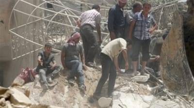 Civilians sit on rubble as others search for survivors at a site hit by a barrel bomb [REUTERS]