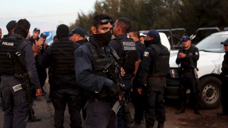 Federal policemen gather outside a ranch where a gunfight between hitmen and federal forces left several casualties in Tanhuato