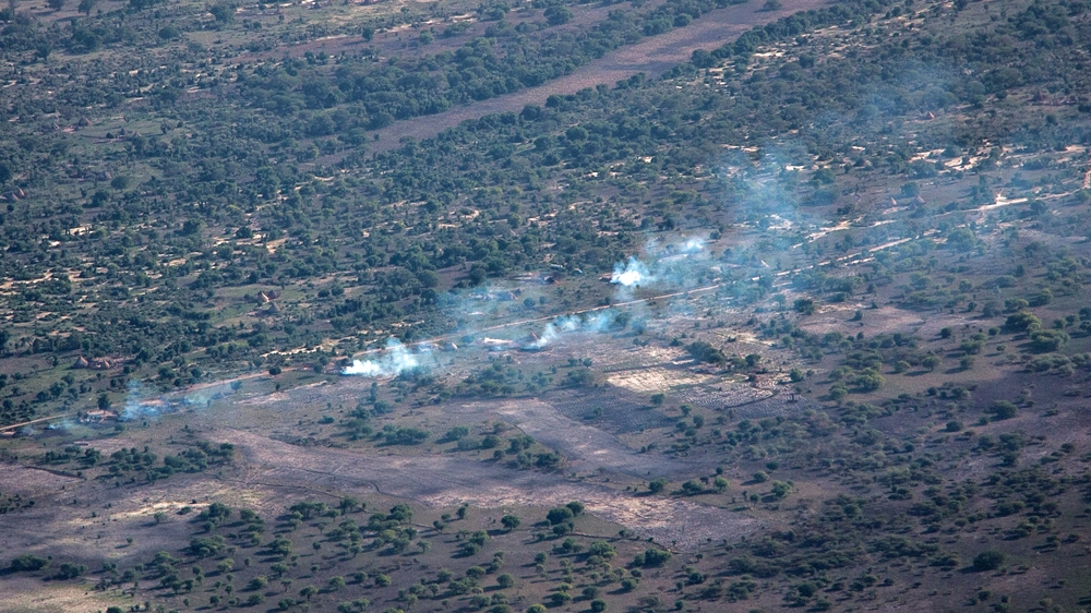 Smoke rises from what appears to be burning huts in a village below during the flight over Leer and Koch counties in Unity State [Ashley Hamer/Al Jazeera]
