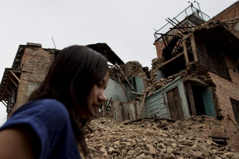 A woman walks past collapsed houses following an earthquake last week in Khokana in Lalitpur