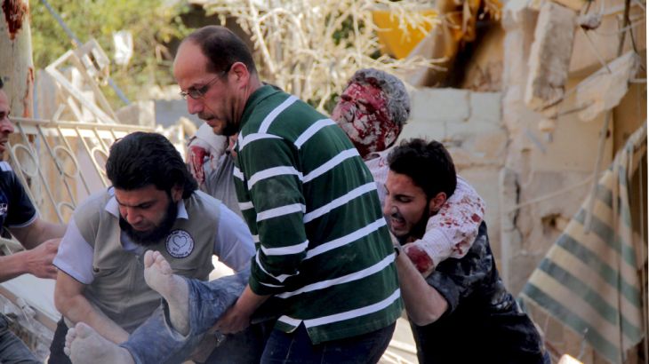Civilians and a civil defence member help an injured man after what activists said was a barrel bomb dropped by forces loyal to Syria''s President Bashar al-Assad and hit a school and a residential bui
