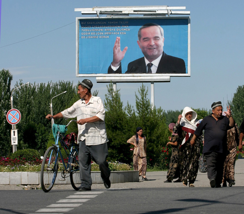 Residents cross the road in the eastern Uzbek city of Andijan under a portrait of President Islam Karimov [EPA]