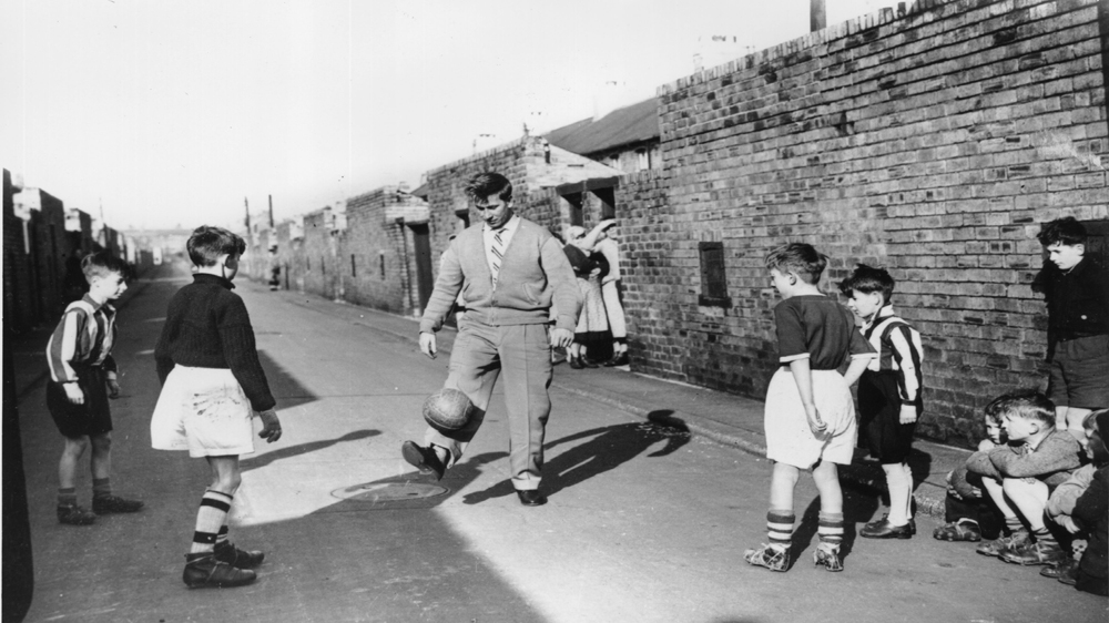 Manchester United's Bobby Charlton plays with some young fans near his home as he recuperates from the injuries he sustained in the air crash that killed many of his teammates [Getty Images]