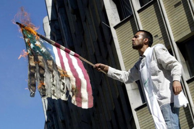 An Iranian hardliner wearing a death shroud burns a US flag outside the British embassy in Tehran in 2004 [Getty]