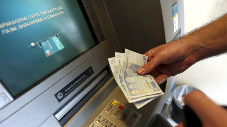 A man withdraws sixty Euros, the maximum amount allowed after the imposed capital controls in Greek banks, at a National Bank of Greece ATM in Piraeus
