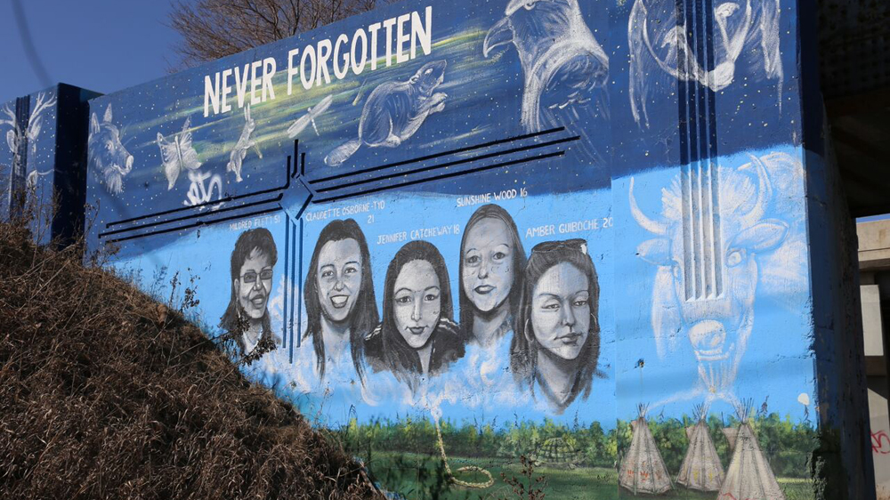 A government-funded mural on Winnipeg’s rail bridge shows the faces of ten murdered and missing native women [Karim Shah / Al Jazeera]
