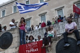 An anti-austerity protester waves a Greek flag above a banner which reads: "The other Europe with Tsipras" during a rally in front of the parliament in Athens, Greece [AP]