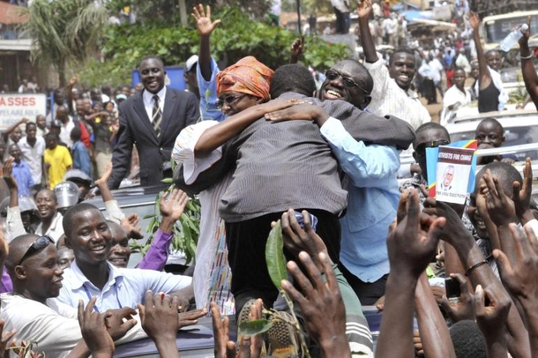 Uganda''s FDC leader Besigye and wife embrace a supporter as they drive from Entebbe international airport
