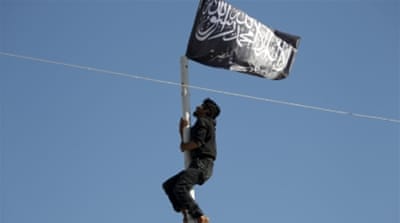 A Nusra Front member climbs a pole where a Nusra flag was raised in the city of Ariha [REUTERS]