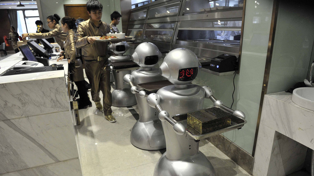 A man puts dishes on robots for delivery at a restaurant in Hefei, Anhui province [Reuters]