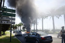 A policeman secures the traffic as taxi drivers, who are on strike, burn tyres to block the access to Nice International airport during a national protest against car-sharing service Uber in Nice