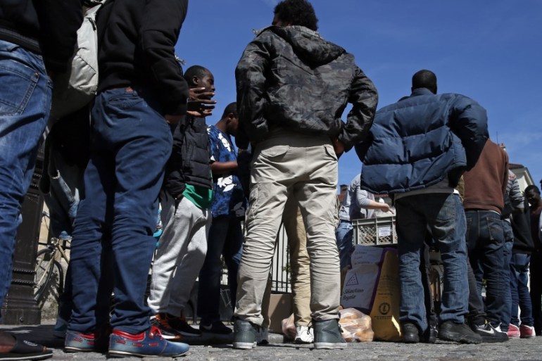 Migrants line up to receive food in front of the Saint-Bernard Church in Paris