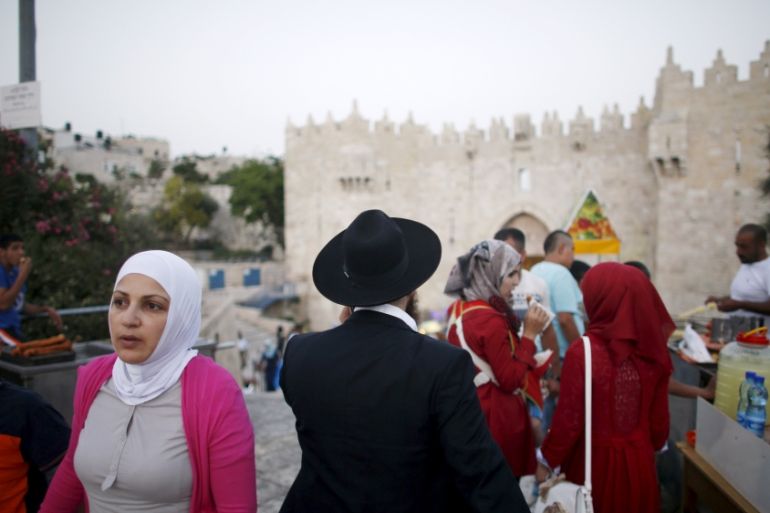 A Muslim woman and an ultra-orthodox Jewish man walk near the Damascus Gate in Jerusalem''s Old City [REUTERS]