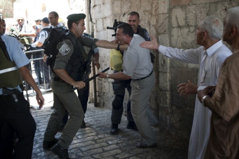An Israeli border patrol police man beats a Palestinian man with a truncheon close to an entrance of Al-Aqsa mosque in 2014 [Getty]