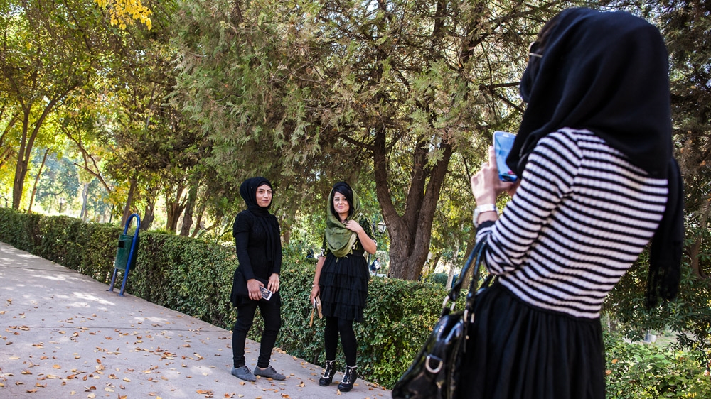 Young Kurdish women have their photo taken by a friend in a park in Sulaymaniyah [Mackenzie Knowles-Coursin]