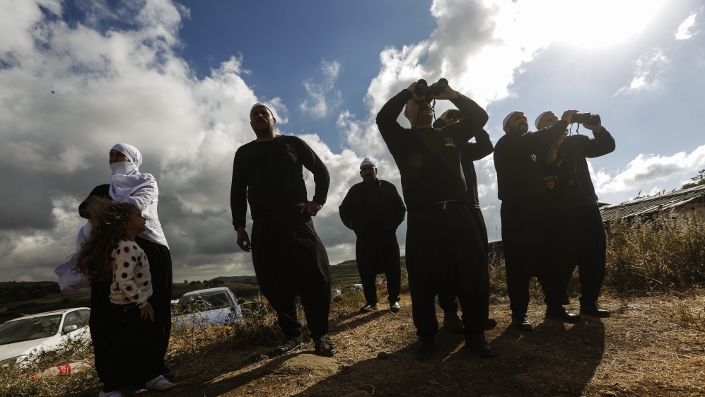 Druze from the Golan Heights watch the fighting near the Druze village of Hadar on the Syrian side of the border [EPA]