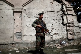 A member of the Afghan security force stands in front of a damaged building a day after attacks outside the Afghan parliament in Kabul [REUTERS]
