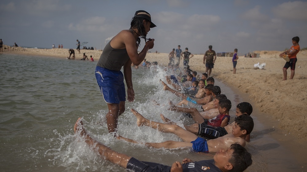 One of Amjed Tantesh's employees at the 'sea pool' instructs children to paddle their feet in the water [Edmée van Rijn/Al Jazeera] 