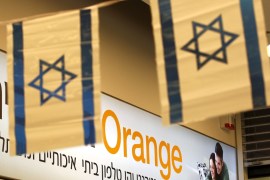 Israeli flags hang next to the logo of Orange mobile company in a store at a Jerusalem mall